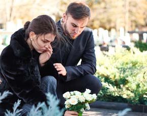 Una pareja llora a un ser querido en la tumba